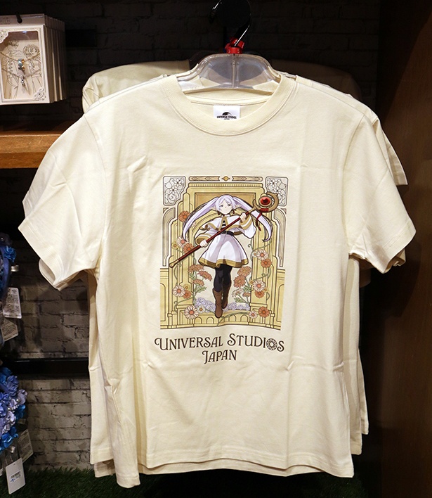 「Tシャツ」(4500円)には、パークに降り立ち、“花畑を出す魔法”を繰り出すフリーレンのビジュアルが。後ろにはパークのゲートが描かれている