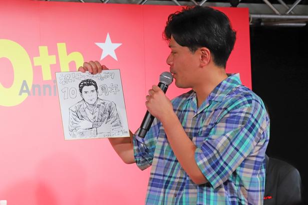 贈られた似顔絵を眺める阪本さん。ステージには「すげえ！」「かっこいい」と声が飛び交っていた