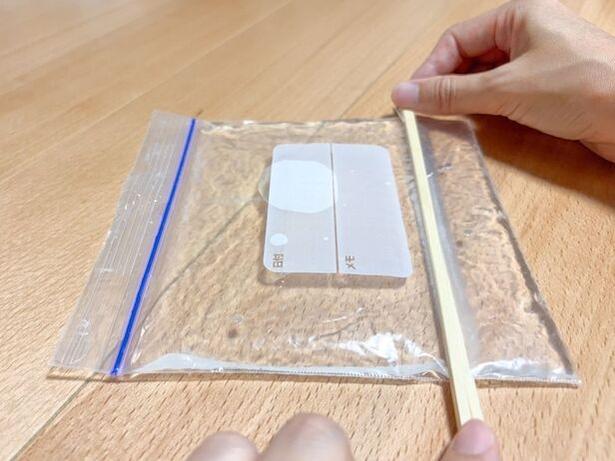 水の入ったジップ付き保存袋を割りばしで挟む(▶次へ) 撮影/こぽり
