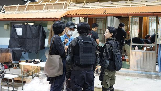 ジアンのセットの前で銃撃体験の説明を受けるツアー参加者たち