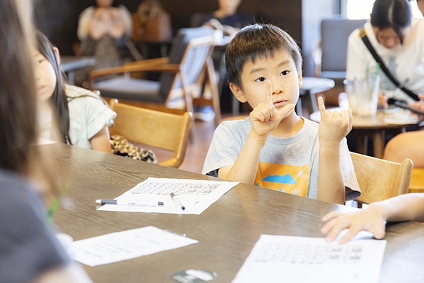 指文字で名前を伝える小学生